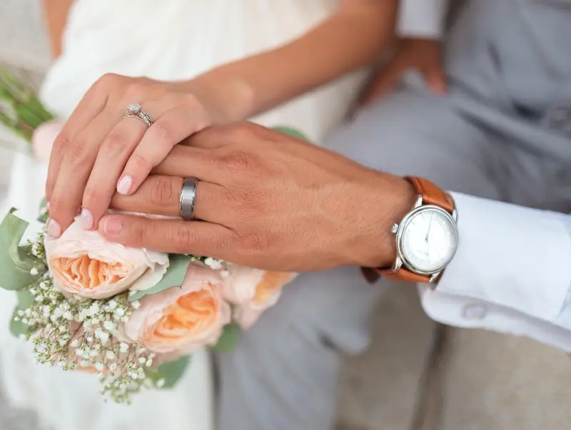 A man and woman holding hands, showcasing their wedding rings, symbolizing their commitment to each other.